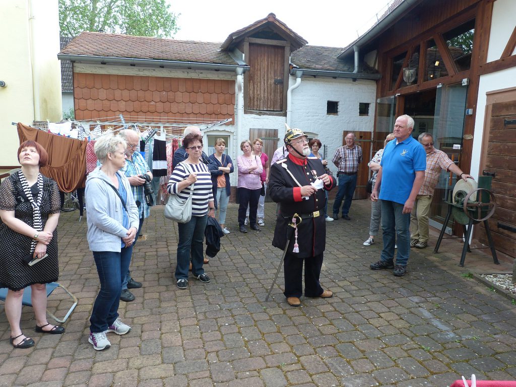 Gendarm Schuster und Zuhörer im Hof des Unterliederbacher Heimatmuseums "Haus Rumpf"